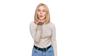 Young blonde woman wearing casual clothes looking at the camera blowing a kiss with hand on air being lovely and sexy. love expression.