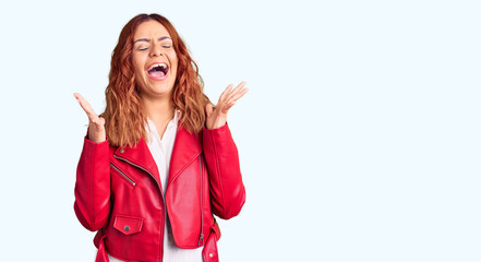 Obraz na płótnie Canvas Young latin woman wearing red leather jacket celebrating mad and crazy for success with arms raised and closed eyes screaming excited. winner concept