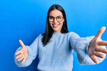 Young brunette woman wearing casual clothes and glasses looking at the camera smiling with open...