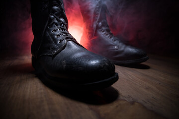 War concept. Old military shoe in a dark toned foggy background. Creative concept of conflict...