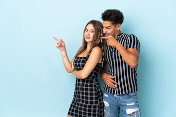 Naklejka premium Teenager caucasian couple isolated on blue background pointing finger to the side in lateral position