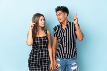 Teenager caucasian couple isolated on blue background intending to realizes the solution while lifting a finger up