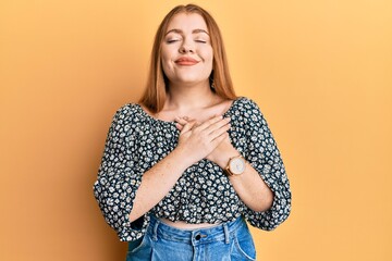 Young beautiful redhead woman wearing shirt with floral print smiling with hands on chest, eyes closed with grateful gesture on face. health concept.