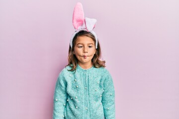 Little beautiful girl wearing cute easter bunny ears making fish face with lips, crazy and comical...