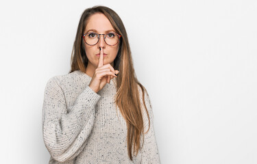 Young blonde woman wearing casual sweater and glasses asking to be quiet with finger on lips....