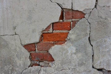 Red bricks visible from under the flaking plaster  