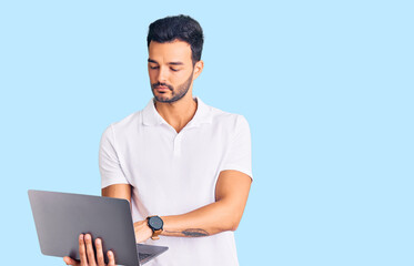 Young handsome hispanic man working using computer laptop thinking attitude and sober expression looking self confident