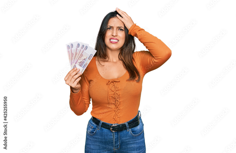 Sticker Beautiful hispanic woman holding russian 500 ruble banknotes stressed and frustrated with hand on head, surprised and angry face