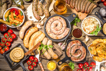 Assortment of different fried sausages. Set with various meat Bavarian, Frankfurt, German grilled sausages, Oktoberfest or summer BBQ party concept, old wooden background copy space top view