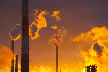 Environmental pollution. Factory pipes. Sunset background