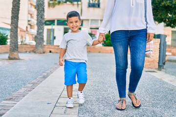 Adorable latin mother and son walking at the city.
