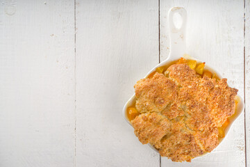 Delicious Summer Peach Cobbler, Homemade sweet summer pie with peaches and vanilla ice cream on white wooden background copy space
