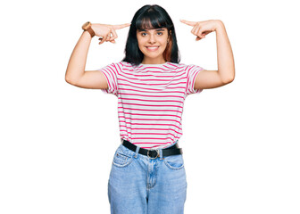 Young hispanic girl wearing casual clothes smiling pointing to head with both hands finger, great idea or thought, good memory