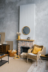 A Scandinavian living room in the grey and gold colors of 2021.  The interior of a country house with fireplace and wicker chair