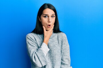 Young hispanic woman wearing casual clothes looking fascinated with disbelief, surprise and amazed expression with hands on chin