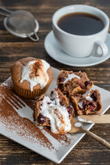 Sweet cherry muffin with ice cream and white cup with tea on a wooden background