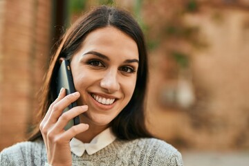 Young hispanic woman smiling happy talking on the smartphone at the city.