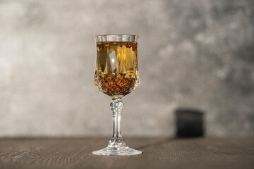 Homemade birch buds tincture in a wine crystal glass on a wooden table background