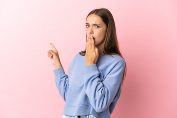 Young woman over isolated pink background with surprise expression while pointing side