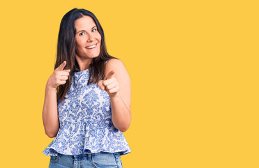 Young beautiful brunette woman wearing casual t-shirt pointing fingers to camera with happy and funny face. good energy and vibes.