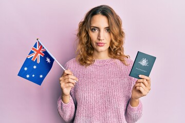 Young caucasian woman holding australian flag and passport relaxed with serious expression on face. simple and natural looking at the camera. © Krakenimages.com