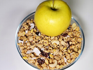 Green apple and breakfast cereal in a bowl on a white background