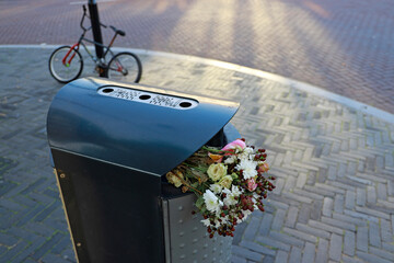flowers in garbage bin on the street