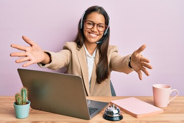 Beautiful hispanic woman working at the office wearing operator headset looking at the camera...