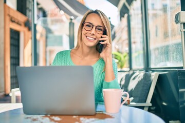 Fototapeta premium Young blonde woman working at the coffee shop terrace.