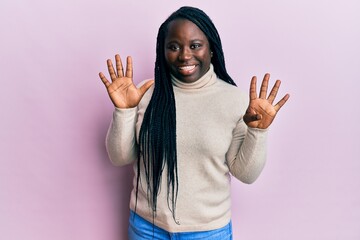 Young black woman with braids wearing casual winter sweater showing and pointing up with fingers...