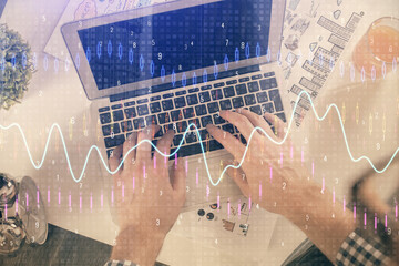 Double exposure of man's hands typing over laptop keyboard and forex chart hologram drawing. Top view. Financial markets concept.