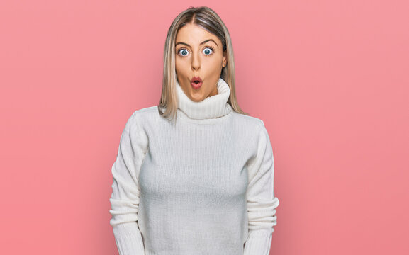 Beautiful blonde woman wearing casual turtleneck sweater afraid and shocked with surprise expression, fear and excited face.