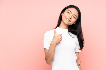 Teenager Chinese woman isolated on pink background giving a thumbs up gesture