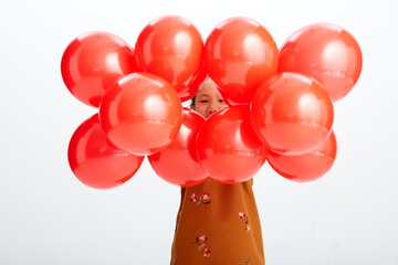 Cute Asian little girl playing with festive red balloons. Wearing traditional Chinese New Year costumes