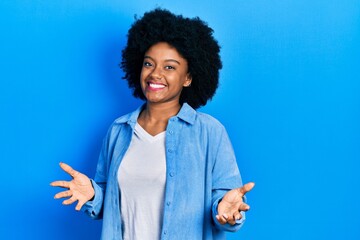 Young african american woman wearing casual clothes smiling cheerful with open arms as friendly welcome, positive and confident greetings