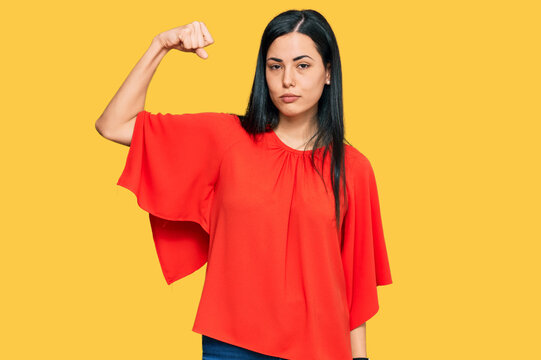 Beautiful young woman wearing casual clothes strong person showing arm muscle, confident and proud of power