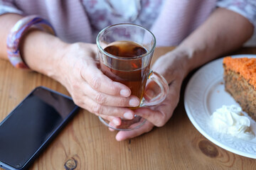 Close-up on woman's hand in coffee shop, enjoying an herbal tea and a slice of carrot cake