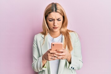 Young caucasian woman wearing business clothes using smartphone skeptic and nervous, frowning upset because of problem. negative person.