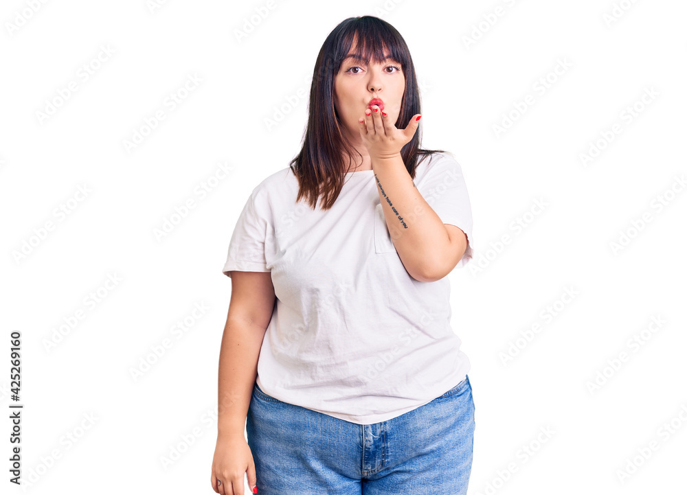 Sticker young plus size woman wearing casual clothes looking at the camera blowing a kiss with hand on air b