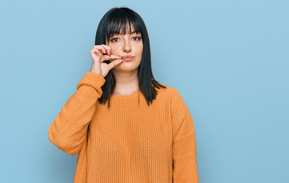 Young hispanic woman wearing casual clothes mouth and lips shut as zip with fingers. secret and silent, taboo talking