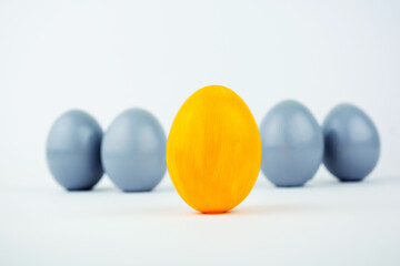 Concept of individuality, exclusivity, better choice. One yellow egg among gray eggs on white background