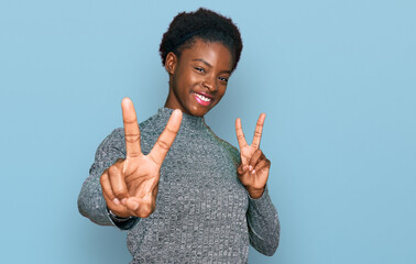 Young african american girl wearing casual clothes smiling looking to the camera showing fingers...