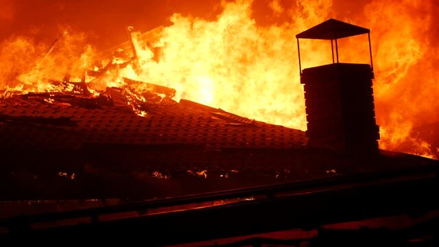 fire close-up. fire on the roof of the house. a burning at building house . home insurance apartment concept. huge fire blazes houses 911 night. property damage arson protection