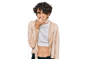 Handsome man wearing make up and woman clothes smelling something stinky and disgusting, intolerable smell, holding breath with fingers on nose. bad smell