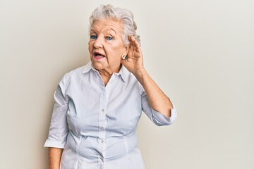 Senior grey-haired woman wearing casual clothes smiling with hand over ear listening and hearing to rumor or gossip. deafness concept.