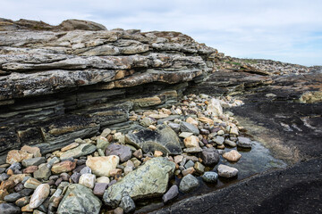 Natural seashore stones and slate rock, Arctic Ocean coastline in Varanger peninsula, Finnmark, Norway