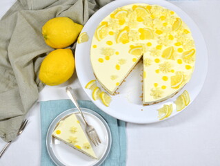 Lemon Curd Cheesecake auf Tortenplatte, ein Stück abgeschnitten und auf Teller, von oben
