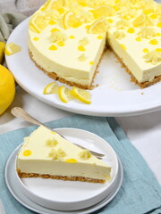 Lemon Curd Cheesecake auf Tortenplatte, ein Stück abgeschnitten und auf Teller