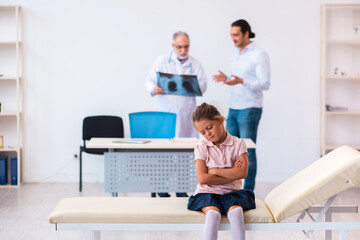 Obraz premium Small girl with her father visiting old male doctor radiologist