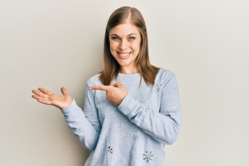 Beautiful caucasian woman wearing casual clothes amazed and smiling to the camera while presenting with hand and pointing with finger.